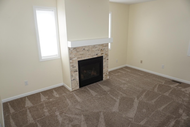unfurnished living room featuring a tile fireplace and carpet