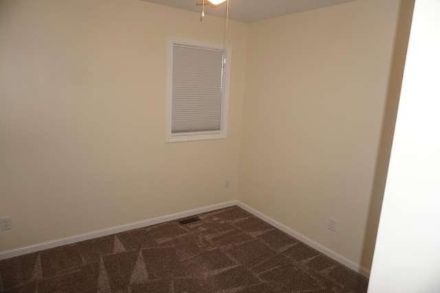 spare room featuring dark carpet and baseboards