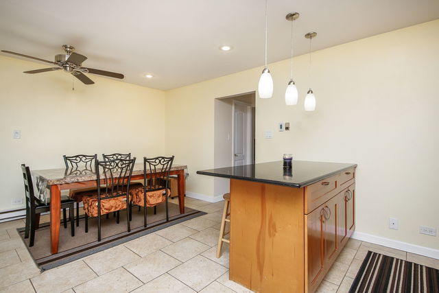 1S215 Stratford Ln, Villa Park, IL 60181 - kitchen with dark countertops, ceiling fan, light tile patterned floors, a kitchen breakfast bar, and pendant lighting
