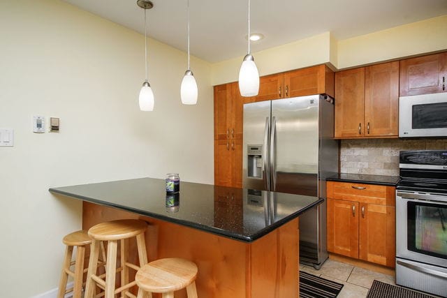 1S215 Stratford Ln, Villa Park, IL 60181 - kitchen with appliances with stainless steel finishes, tasteful backsplash, brown cabinetry, a breakfast bar, and light tile patterned flooring