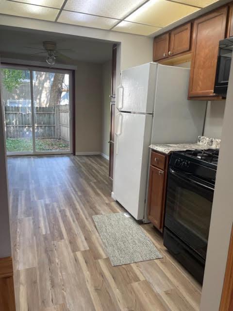 2049 Berkshire Cir Unit D, Carpentersville, IL 60110 - kitchen with black gas range, brown cabinets, light wood-style flooring, light countertops, and a drop ceiling