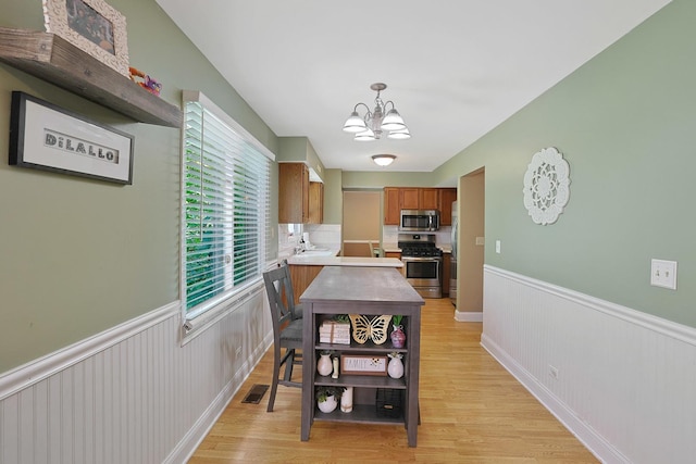 710 Cimarron Dr, Cary, IL 60013 - dining area featuring a chandelier, a wainscoted wall, and light wood-style flooring