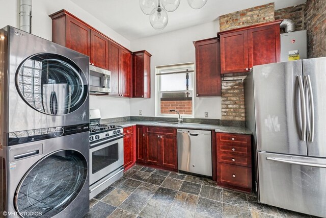 1734 W Erie St Unit 3, Chicago, IL 60622 - kitchen featuring appliances with stainless steel finishes, reddish brown cabinets, estacked washer and dryer, and dark stone finish flooring