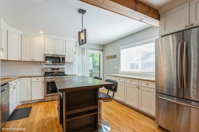 26W323 Harrison Ave, Winfield, IL 60190 - kitchen with stainless steel appliances, light wood-style floors, tasteful backsplash, light stone counters, and hanging light fixtures