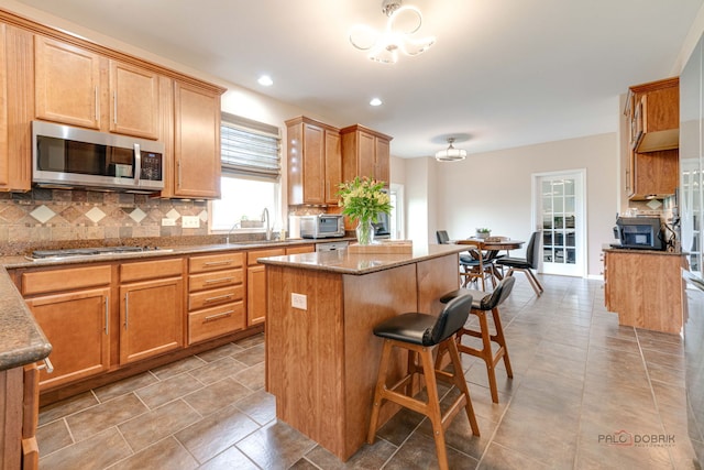 1174 Pine Tree Ct, Lake Villa, IL 60046 - kitchen with stainless steel appliances, a center island, tasteful backsplash, a kitchen bar, and light stone counters