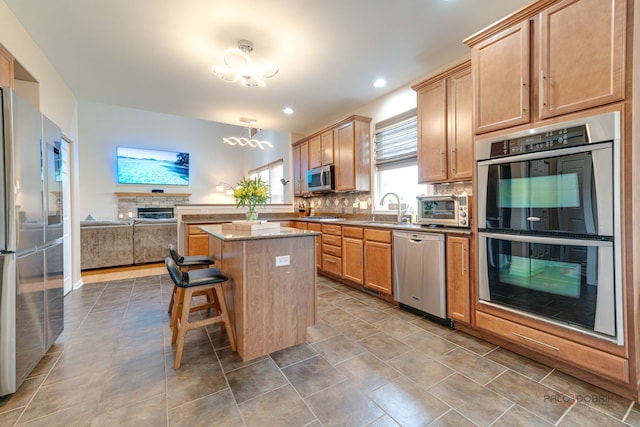 1174 Pine Tree Ct, Lake Villa, IL 60046 - kitchen with appliances with stainless steel finishes, decorative backsplash, a kitchen island, open floor plan, and a kitchen bar
