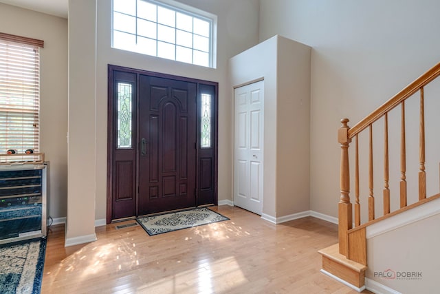 1174 Pine Tree Ct, Lake Villa, IL 60046 - entrance foyer with wine cooler, stairway, wood finished floors, and a high ceiling