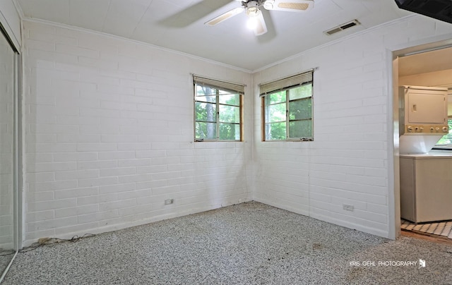 143 Eagle Point Rd, Fox Lake, IL 60020 - unfurnished room featuring ornamental molding, stacked washing machine and dryer, ceiling fan, speckled floor, and brick wall