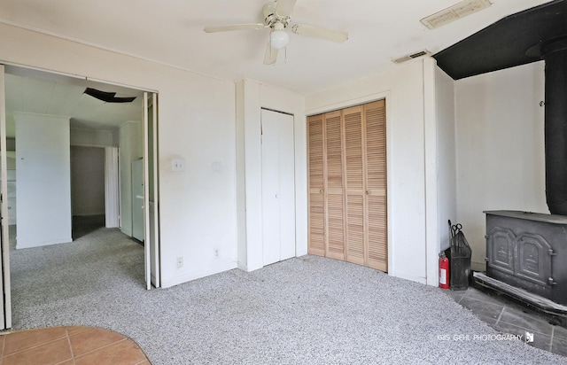 143 Eagle Point Rd, Fox Lake, IL 60020 - unfurnished bedroom featuring a wood stove, a closet, carpet floors, ceiling fan, and tile patterned flooring
