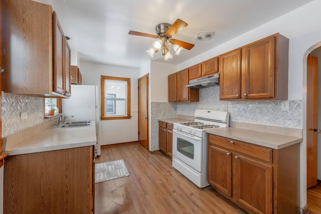 3466 186th St, Lansing, IL 60438 - kitchen featuring white appliances, under cabinet range hood, arched walkways, a ceiling fan, and backsplash