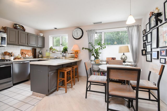 801 S Plymouth Ct Unit V, Chicago, IL 60605 - kitchen featuring stainless steel appliances, backsplash, light countertops, a peninsula, and a kitchen bar