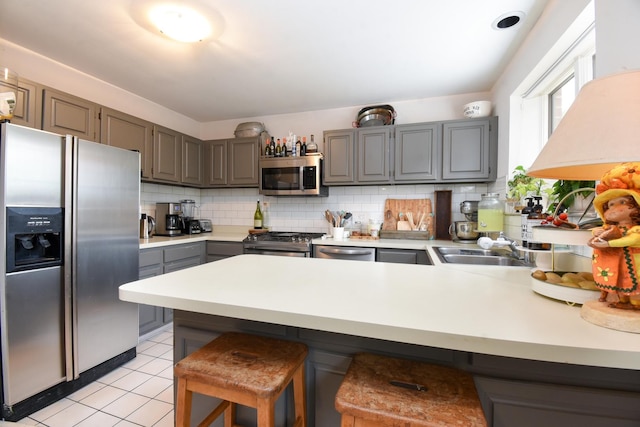 801 S Plymouth Ct Unit V, Chicago, IL 60605 - kitchen featuring appliances with stainless steel finishes, a peninsula, gray cabinetry, backsplash, and light countertops