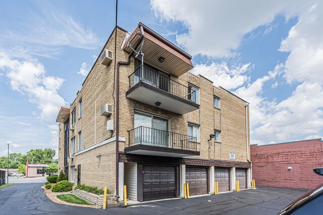 9819 S Cicero Ave Unit 6, Oak Lawn, IL 60453 - view of building exterior featuring an attached garage, a wall unit AC, and driveway