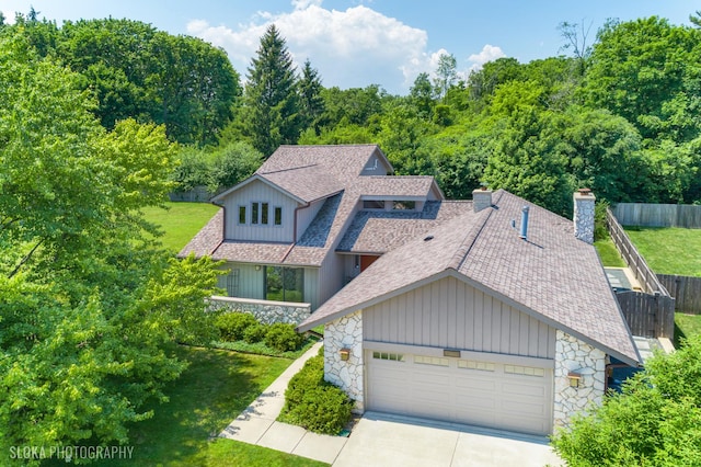 530 Sunnyside Ave, Gurnee, IL 60031 - view of front facade featuring stone siding, a chimney, a shingled roof, concrete driveway, and board and batten siding