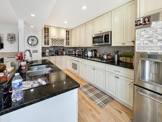 204 Inverrary Ln, Deerfield, IL 60015 - kitchen featuring stainless steel appliances, cream cabinets, light wood-style floors, backsplash, and glass insert cabinets