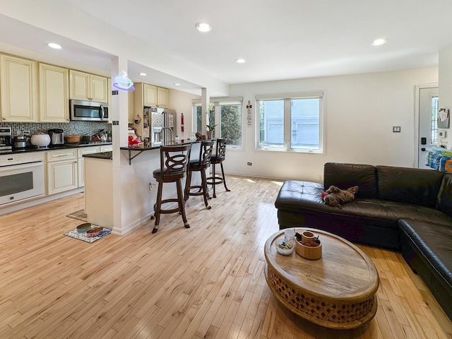 204 Inverrary Ln, Deerfield, IL 60015 - kitchen featuring cream cabinets, stainless steel appliances, open floor plan, dark countertops, and a kitchen bar