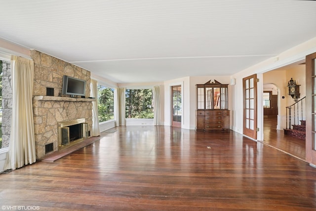 691 Lake Ave, Crystal Lake, IL 60014 - unfurnished living room featuring wood finished floors, a stone fireplace, stairs, and arched walkways