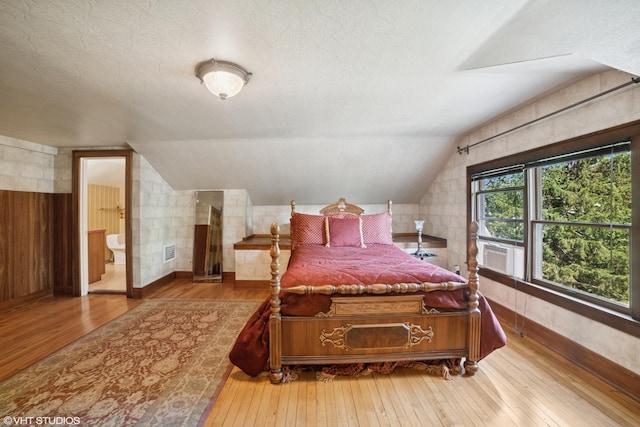 691 Lake Ave, Crystal Lake, IL 60014 - bedroom featuring hardwood / wood-style floors, vaulted ceiling, cooling unit, ensuite bathroom, and wood walls