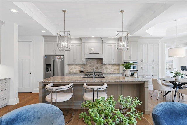 1311 Hickory Tree Ct, Mahomet, IL 61853 - kitchen featuring stainless steel appliances, decorative backsplash, a center island with sink, wood finished floors, and a breakfast bar area