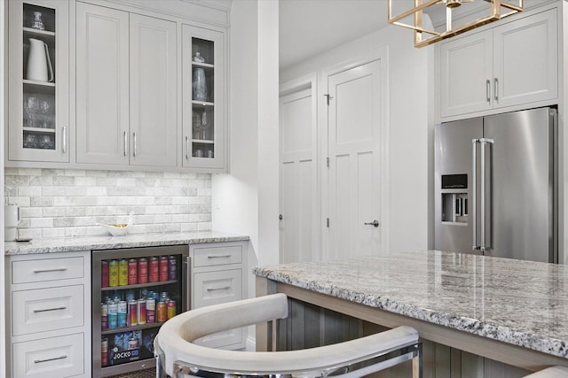 1311 Hickory Tree Ct, Mahomet, IL 61853 - kitchen featuring high end fridge, tasteful backsplash, a chandelier, and light stone countertops