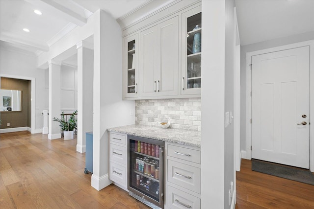 1311 Hickory Tree Ct, Mahomet, IL 61853 - indoor dry bar featuring wine cooler, crown molding, decorative backsplash, light wood finished floors, and recessed lighting