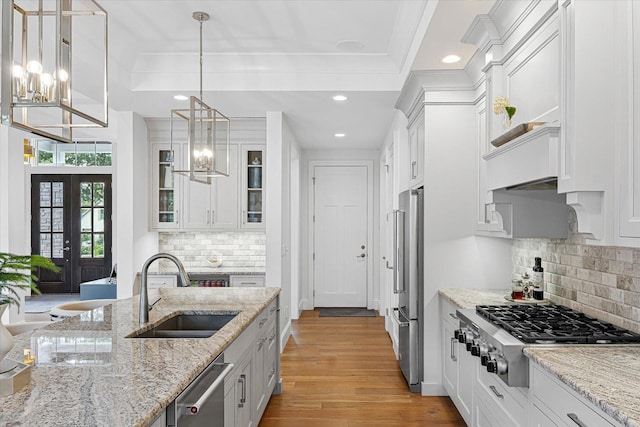 1311 Hickory Tree Ct, Mahomet, IL 61853 - kitchen with appliances with stainless steel finishes, light wood finished floors, glass insert cabinets, white cabinets, and hanging light fixtures