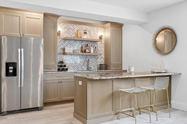 1311 Hickory Tree Ct, Mahomet, IL 61853 - kitchen featuring stainless steel refrigerator with ice dispenser, light stone countertops, decorative backsplash, a peninsula, and light wood-style floors
