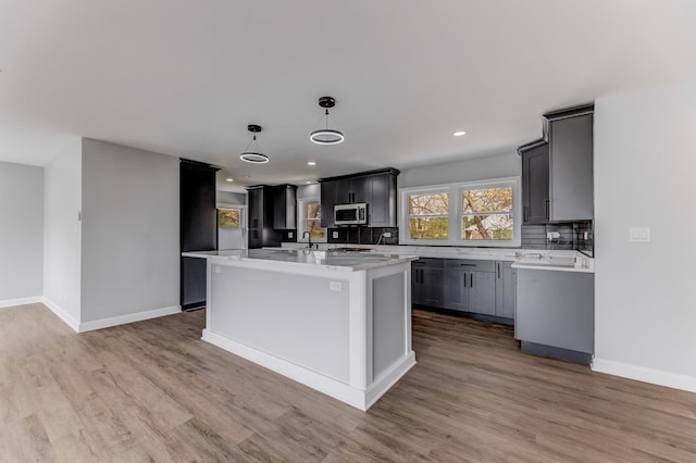 14911 Woodlawn Ave, Dolton, IL 60419 - kitchen featuring stainless steel microwave, light countertops, light wood-type flooring, a kitchen island, and recessed lighting