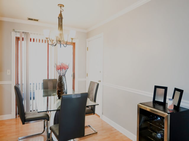 2545 N 72nd Ct Unit 4, Elmwood Park, IL 60707 - dining area featuring a chandelier, light wood-style flooring, beverage cooler, and crown molding