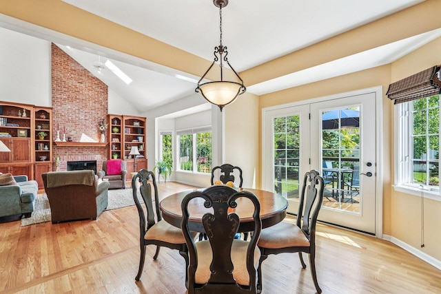 2524 Wild Timothy Rd, Naperville, IL 60564 - dining space featuring lofted ceiling, light wood finished floors, a skylight, and a brick fireplace