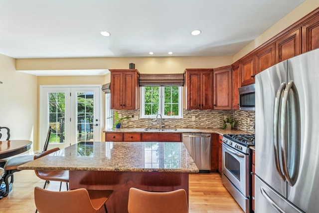 2524 Wild Timothy Rd, Naperville, IL 60564 - kitchen with appliances with stainless steel finishes, a kitchen breakfast bar, decorative backsplash, light wood-style flooring, and a center island
