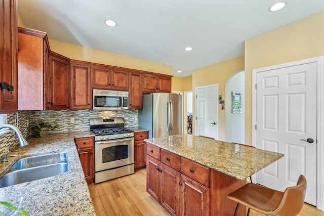 2524 Wild Timothy Rd, Naperville, IL 60564 - kitchen featuring stainless steel appliances, arched walkways, decorative backsplash, light wood-style floors, and a breakfast bar area