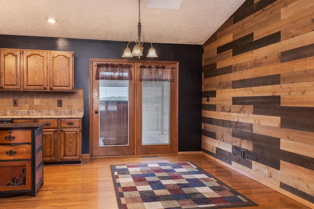 1413 Bethany Ln, Pontiac, IL 61764 - dining space featuring a chandelier, wooden walls, lofted ceiling, and light wood-type flooring