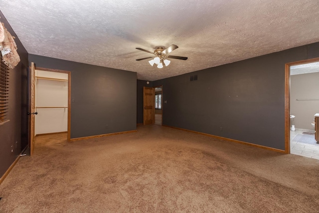 1413 Bethany Ln, Pontiac, IL 61764 - unfurnished bedroom featuring a textured ceiling, carpet flooring, ensuite bath, a spacious closet, and a ceiling fan