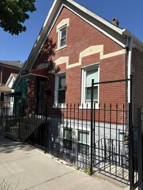 3417 S Morgan St, Chicago, IL 60608 - view of home's exterior with brick siding, a fenced front yard, and a chimney