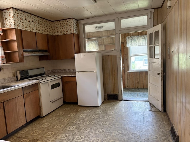 5535 S Fairfield Ave, Chicago, IL 60629 - kitchen with white appliances, wood walls, under cabinet range hood, light countertops, and tasteful backsplash