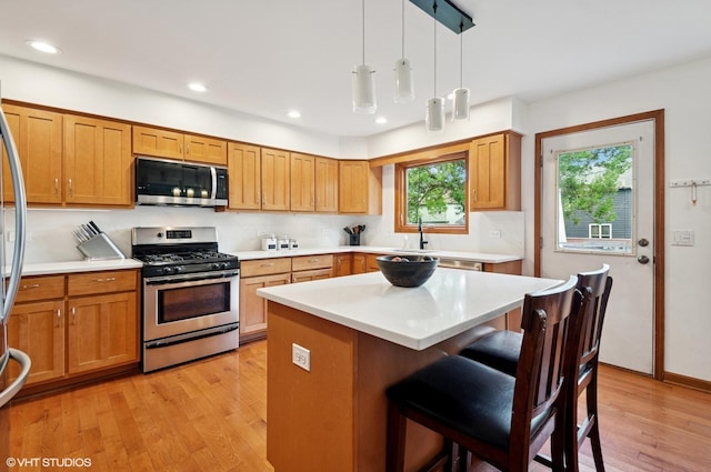 1167 Book Rd, Naperville, IL 60540 - kitchen featuring appliances with stainless steel finishes, a kitchen breakfast bar, light wood-style floors, light countertops, and hanging light fixtures