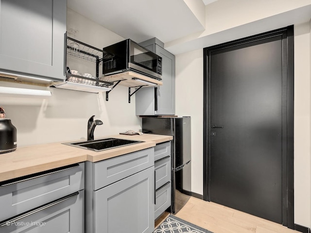 849 Cramer Ct, Willowbrook, IL 60527 - kitchen with stainless steel microwave, wood counters, light wood-style floors, and gray cabinetry
