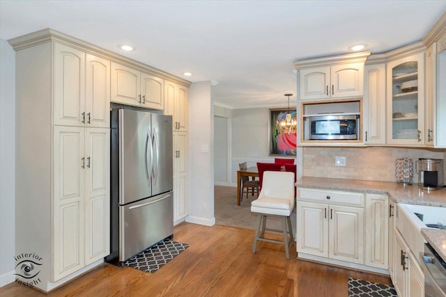19126 Pierce Ave, Homewood, IL 60430 - kitchen with stainless steel appliances, cream cabinets, decorative backsplash, light wood-style floors, and light stone countertops