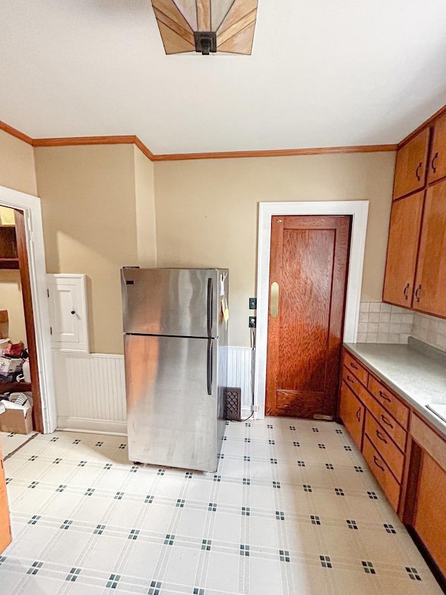 997 S Evergreen Ave, Kankakee, IL 60901 - kitchen featuring freestanding refrigerator, light countertops, brown cabinets, decorative backsplash, and crown molding