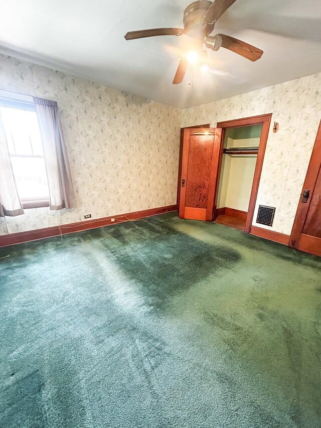 997 S Evergreen Ave, Kankakee, IL 60901 - unfurnished bedroom with dark colored carpet, a ceiling fan, and wallpapered walls