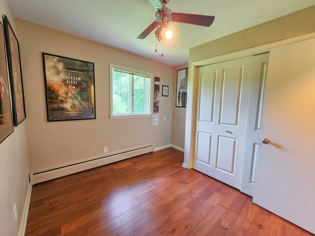 20798 White Oaks Rd, Morrison, IL 61270 - unfurnished bedroom with a baseboard radiator, wood finished floors, a closet, and a ceiling fan