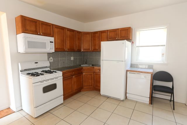 2458 N Clybourn Ave, Chicago, IL 60614 - kitchen featuring white appliances, decorative backsplash, brown cabinets, and light tile patterned flooring