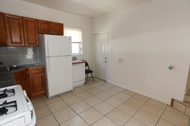 2458 N Clybourn Ave, Chicago, IL 60614 - kitchen with white appliances, backsplash, light tile patterned floors, dark countertops, and brown cabinets