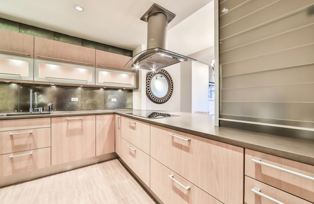2100 N Lincoln Park W Unit 4Dn, Chicago, IL 60614 - kitchen with light brown cabinetry, stovetop, island exhaust hood, backsplash, and glass insert cabinets