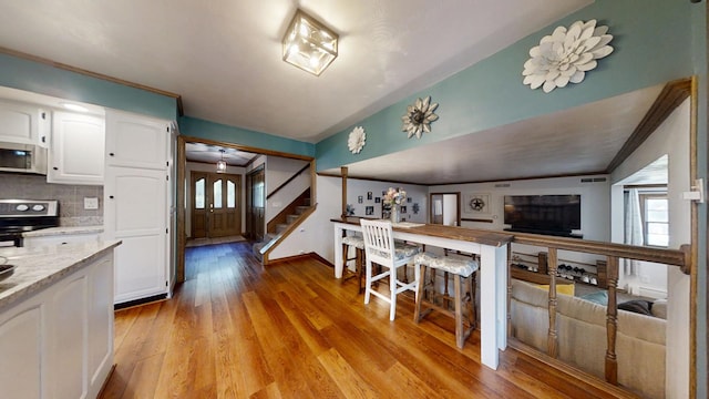 17 Park Dr, Villa Grove, IL 61956 - kitchen with appliances with stainless steel finishes, white cabinets, plenty of natural light, light wood finished floors, and lofted ceiling