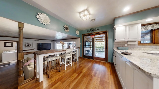 17 Park Dr, Villa Grove, IL 61956 - kitchen with washer / dryer, white cabinetry, light wood-type flooring, and light stone countertops