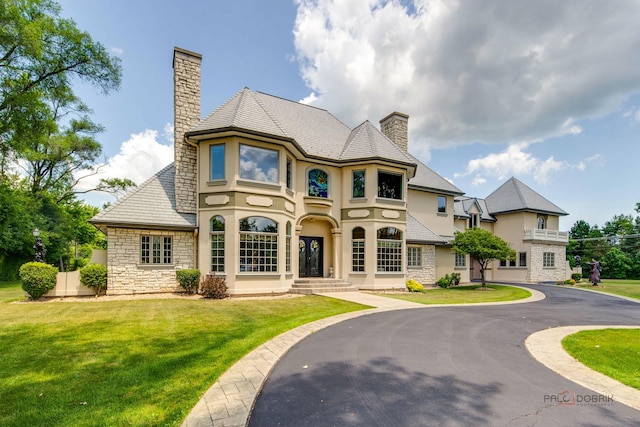 1130 Gavin Ct, Lake Forest, IL 60045 - view of front of property with a chimney, stone siding, stucco siding, a front lawn, and a high end roof