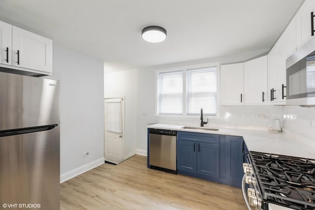 7915 S Justine St, Chicago, IL 60620 - kitchen featuring appliances with stainless steel finishes, blue cabinetry, light countertops, white cabinetry, and light wood-style floors