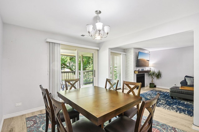 1521 S County Farm Rd Unit 2-2, Wheaton, IL 60189 - dining room featuring a chandelier, light wood-type flooring, and a brick fireplace